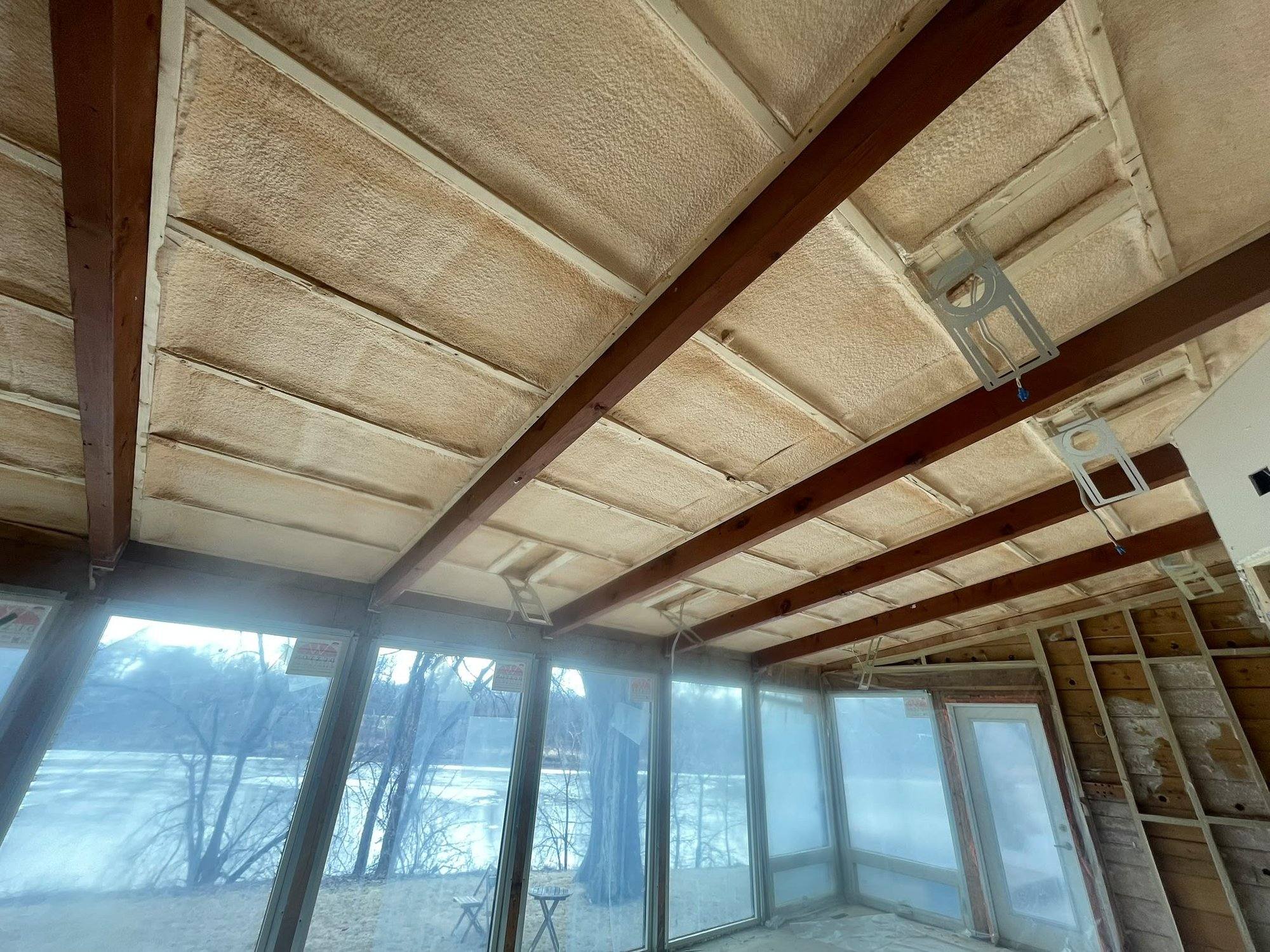 Finished cottage sunroom with spray foamed ceiling and a lake visible through the windows