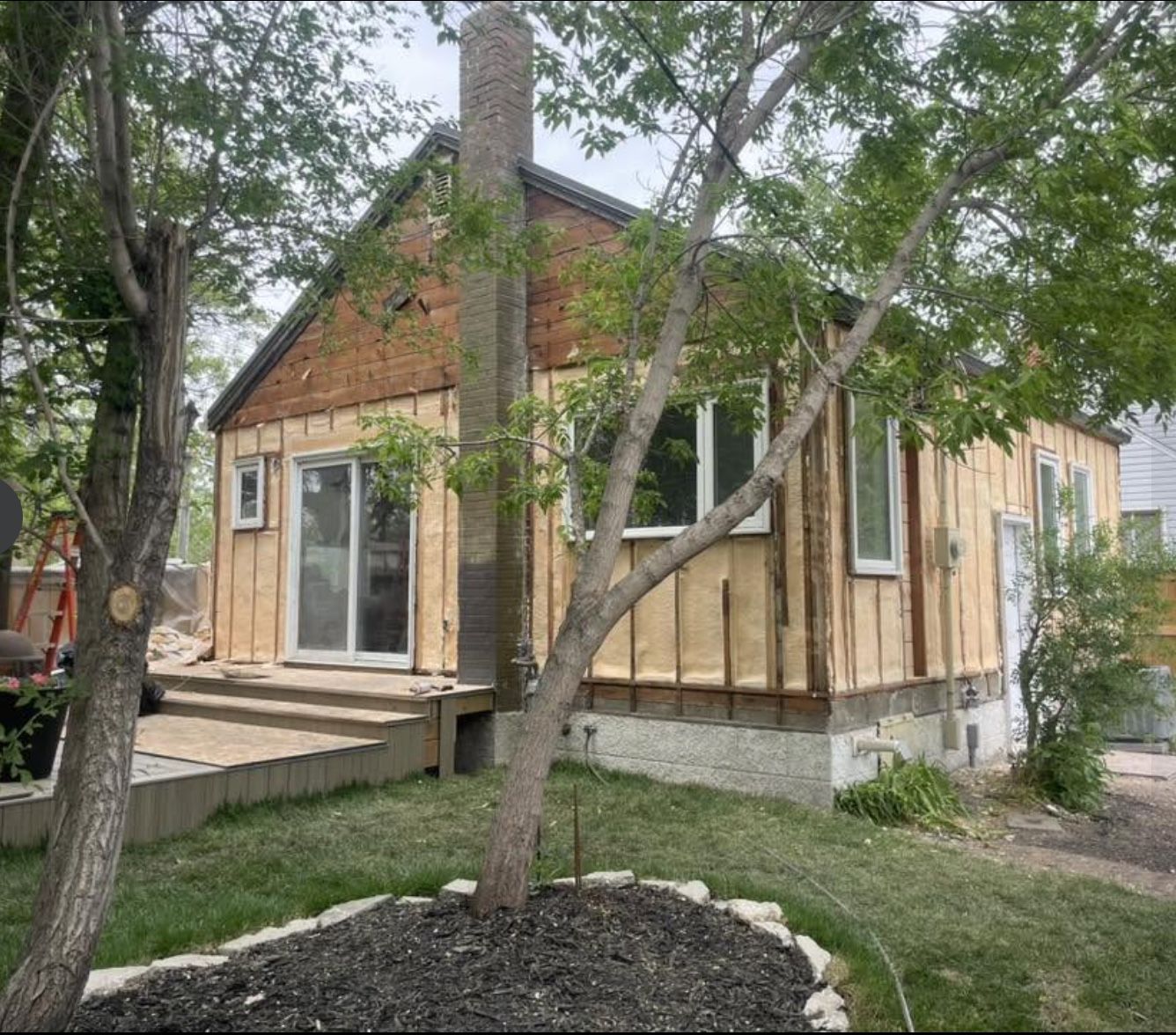 House exterior with spray foam applied over the walls between wood strapping, awaiting new siding