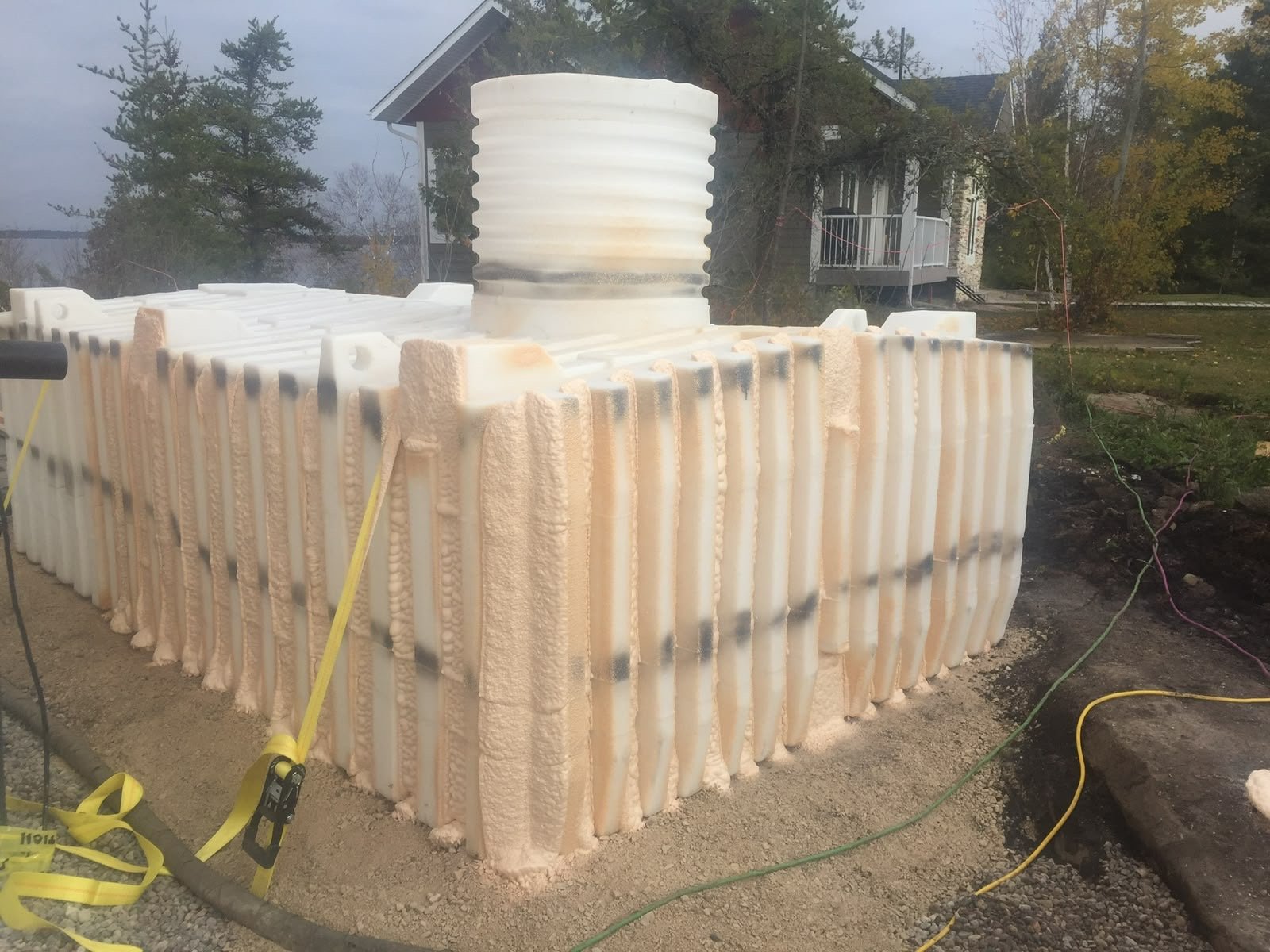 Small towable structure with closed-cell spray foam applied over the entire exterior, strapped and ready for siding, parked on a residential lot