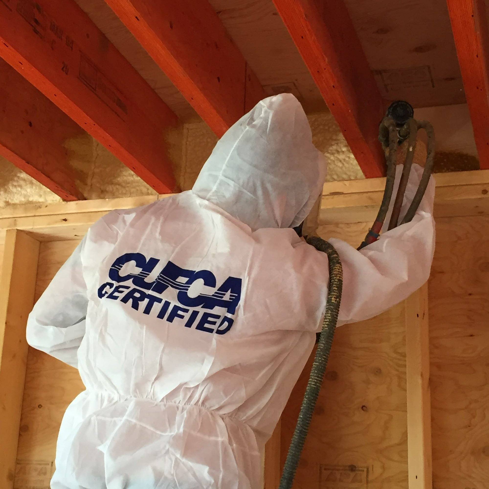CUFCA-certified installer in full protective gear spraying closed-cell foam onto rafters