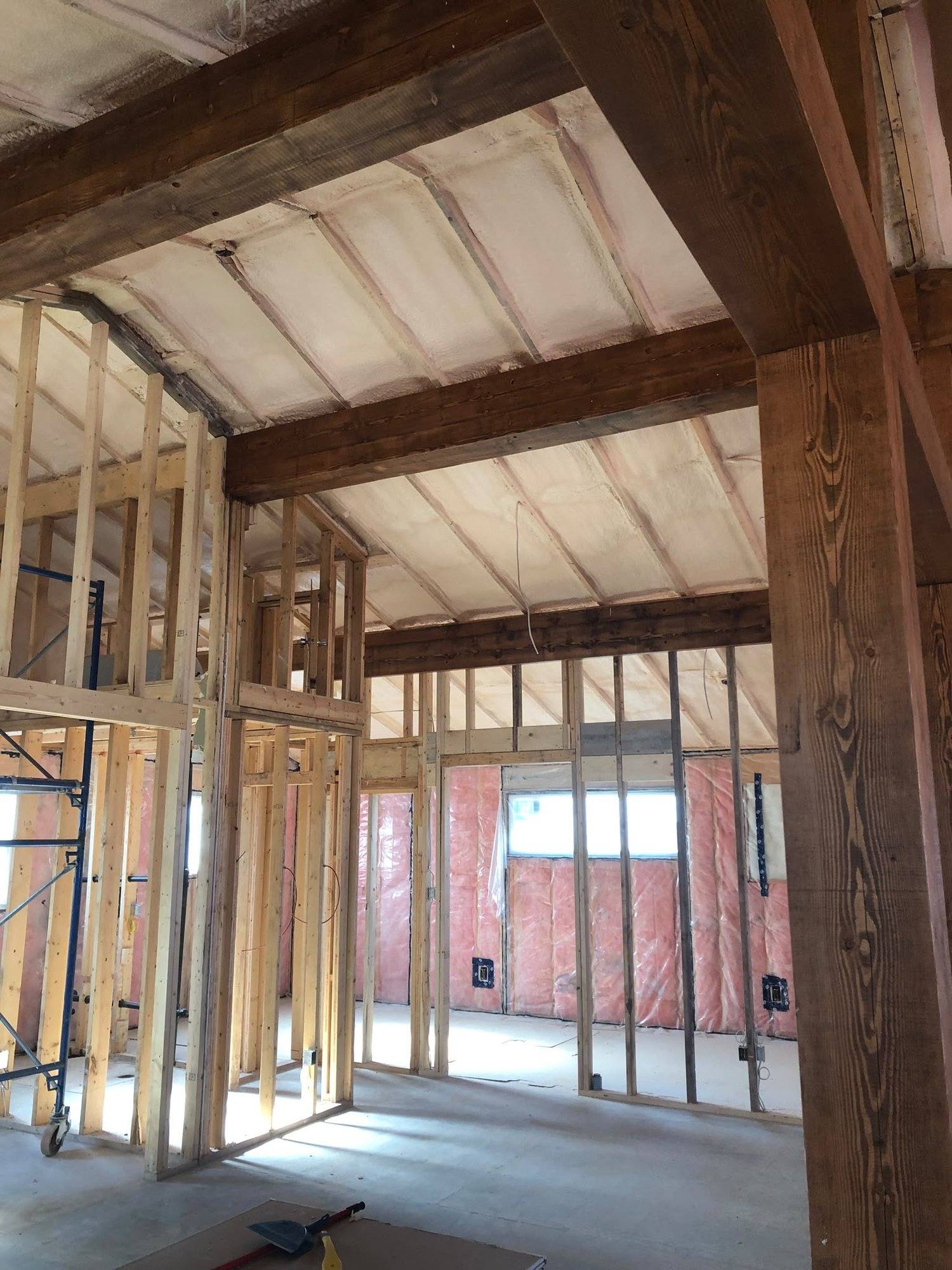 Post-frame shop interior under construction with heavy timber posts and beams, framing open and ready for insulation